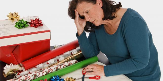 A very tired woman slouching in front of a pile of gift wrapping paper