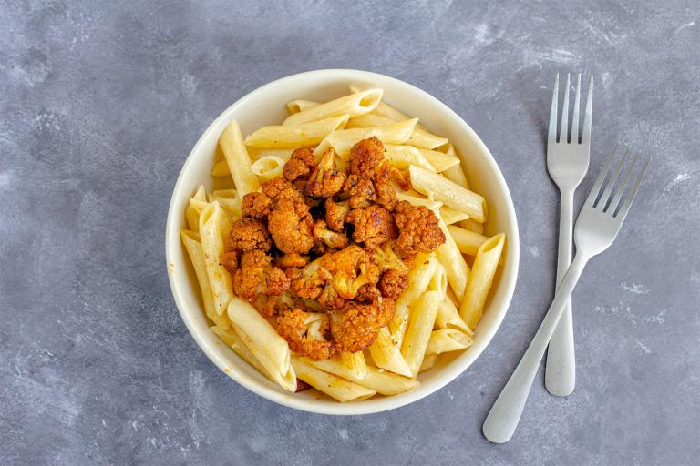 a bowl of penne with spicy roasted cauliflower on top